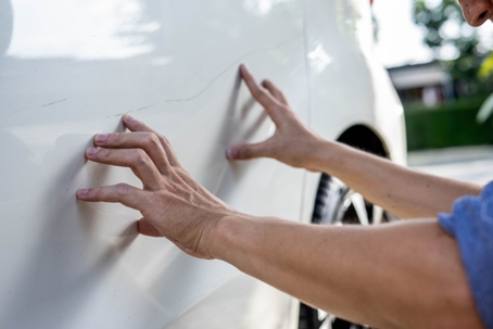 Man checking car scratch dent damage