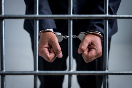 Handcuffed behind bars